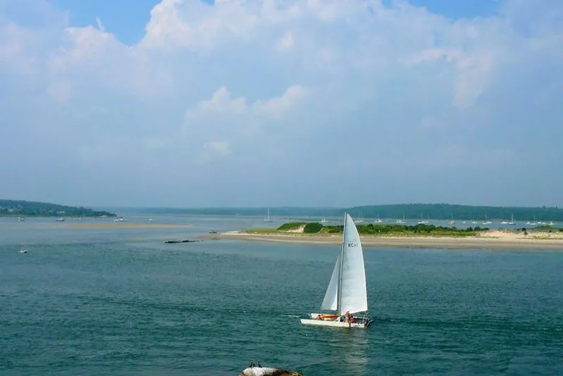 Slide: The Image of Sailboat Aquarius RC 27 (1981) on serene blue waters near a sandy shoreline. - 5