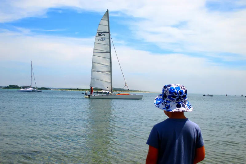 Slide: The Image of Child watching Aquarius RC 27 sailboat on calm water, sunny day, 1981 model. - 7