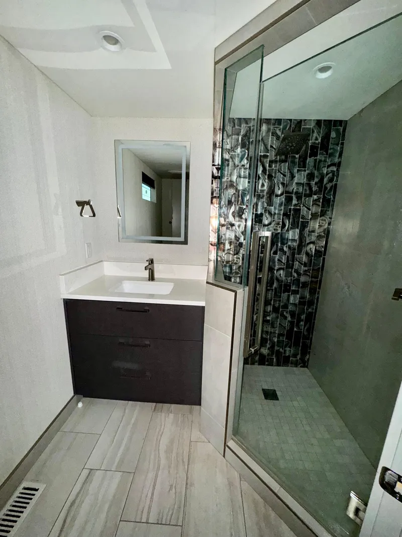 Slide: The Image of Modern bathroom with glass shower, sleek vanity, and tiled floor in Adonia Just Add Water Trip #13, 2021. - 14