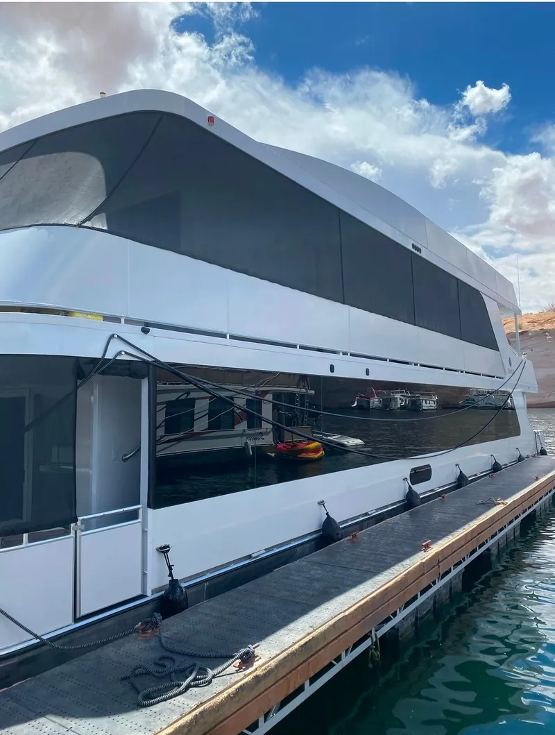 Slide: The Image of Modern Adonia houseboat docked, "Just Add Water Trip #13," 2021 model, under a partly cloudy sky. - 30