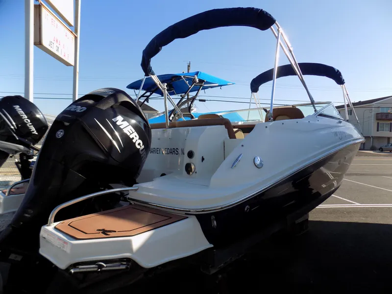 Slide: The Image of 2014 Sea Ray 220 Sundeck boat with Mercury outboard engine, docked in a marina. - 2