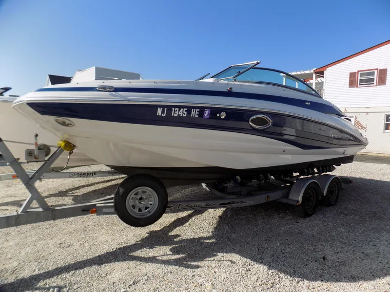 Slide: The Image of 2013 Crownline Eclipse E4 boat on trailer, parked outdoors under clear blue sky. - 0