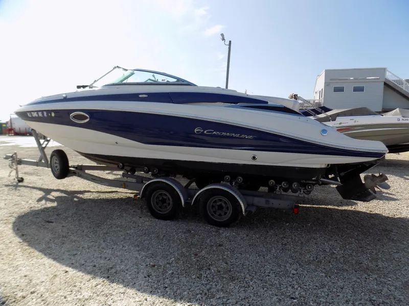 Slide: The Image of 2013 Crownline Eclipse E4 boat on trailer, parked outdoors under clear sky. - 1