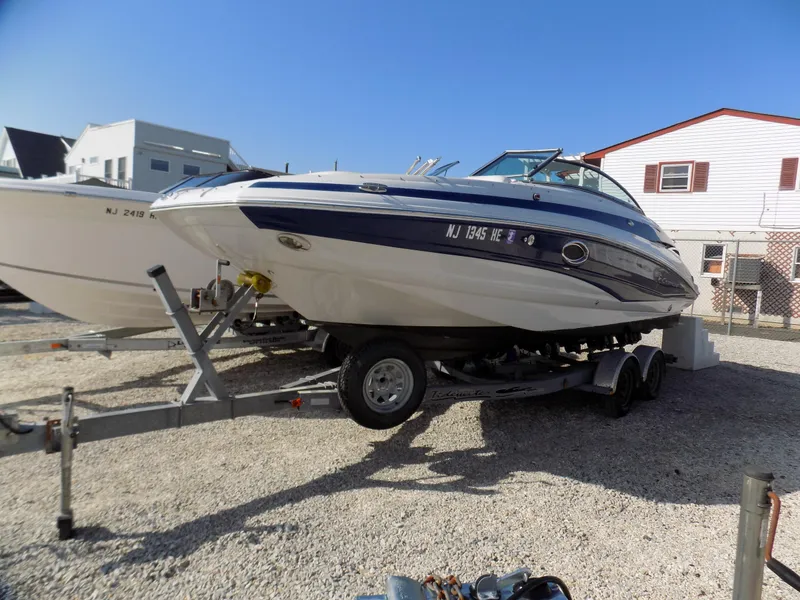 Slide: The Image of 2013 Crownline Eclipse E4 boat on trailer, parked outdoors on gravel. - 2