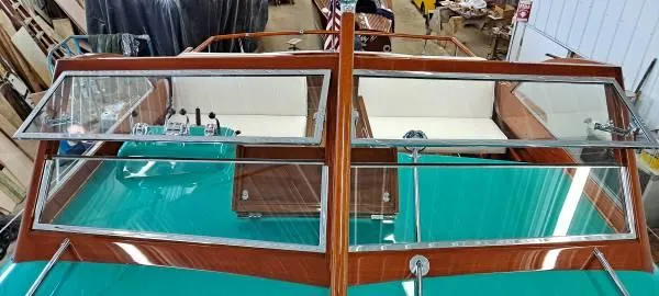 Slide: The Image of 1961 Chris-Craft Roamer boat with teal deck and wooden trim in a workshop setting. - 17