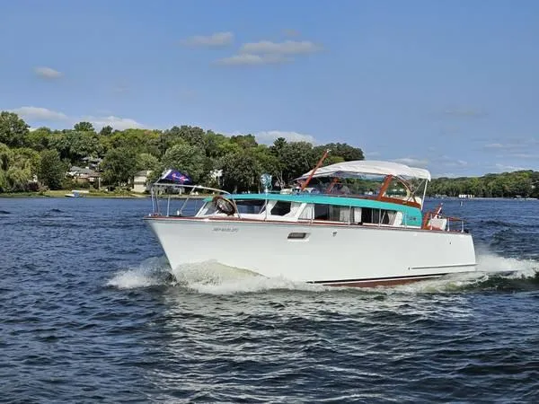 Slide: The Image of 1961 Chris-Craft Roamer boat cruising on a scenic lake with lush green shoreline. - 2