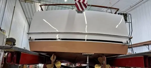 Slide: The Image of 1961 Chris-Craft Roamer boat in a workshop, viewed from the rear with an American flag. - 25