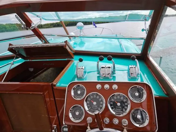 Slide: The Image of 1961 Chris-Craft Roamer boat dashboard with vintage gauges and controls on a serene lake. - 30