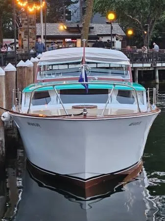Slide: The Image of 1961 Chris-Craft Roamer boat docked at a marina, evening lights reflecting on water. - 31