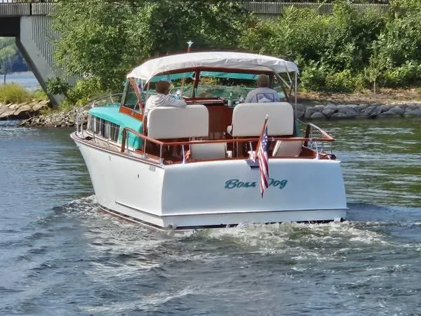 Slide: The Image of 1961 Chris-Craft Roamer boat cruising on a river with lush greenery in the background. - 6