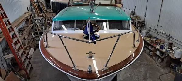 Slide: The Image of 1961 Chris-Craft Roamer boat in workshop, showcasing classic design and teal accents. - 8