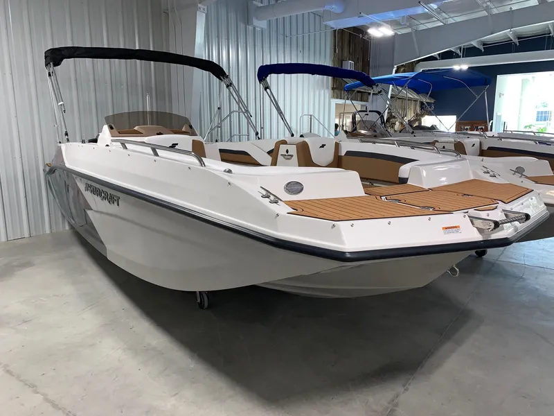 Slide: The Image of 2024 Starcraft SVX 211 boat in showroom, white hull, black canopy, brown interior. - 2