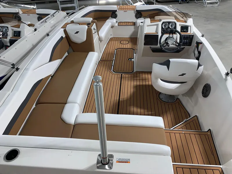 Slide: The Image of 2024 Starcraft SVX 211 boat interior with tan and white seating, wood flooring, and modern dashboard. - 3