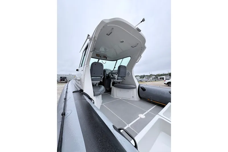 Slide: The Image of 2012 Protector Targa 30 boat interior with seating and controls, docked on a cloudy day. - 5