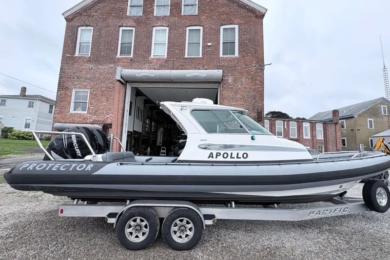 The Image of 2012 Protector Targa 30 boat on trailer, parked in front of a brick building. - 0