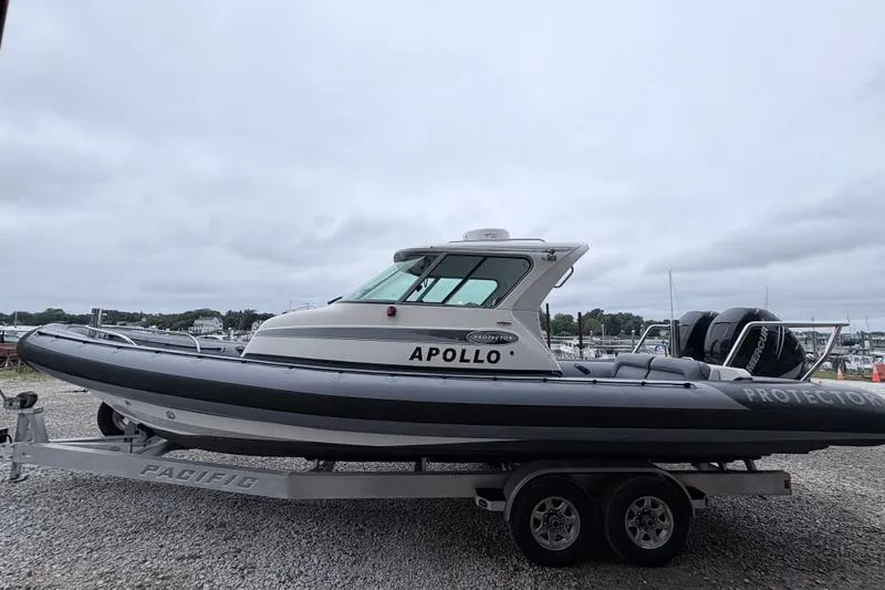Slide: The Image of 2012 Protector Targa 30 boat on trailer, docked at marina under cloudy sky. - 1