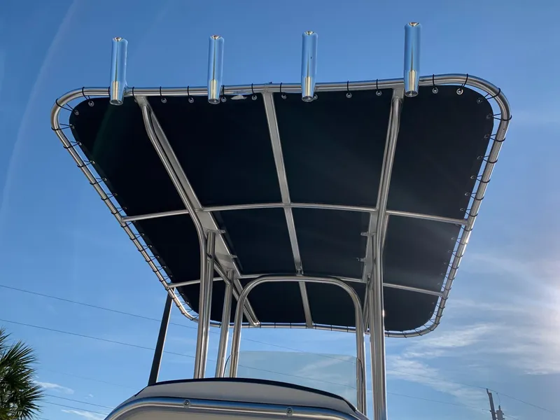 Slide: The Image of 2024 Robalo R202 Explorer T-top with rod holders against blue sky. - 4