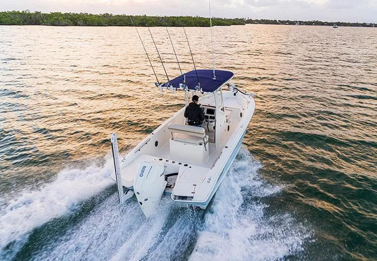 Slide: The Image of 2023 Boston Whaler 220 Dauntless boat cruising on open water at sunset. - 2