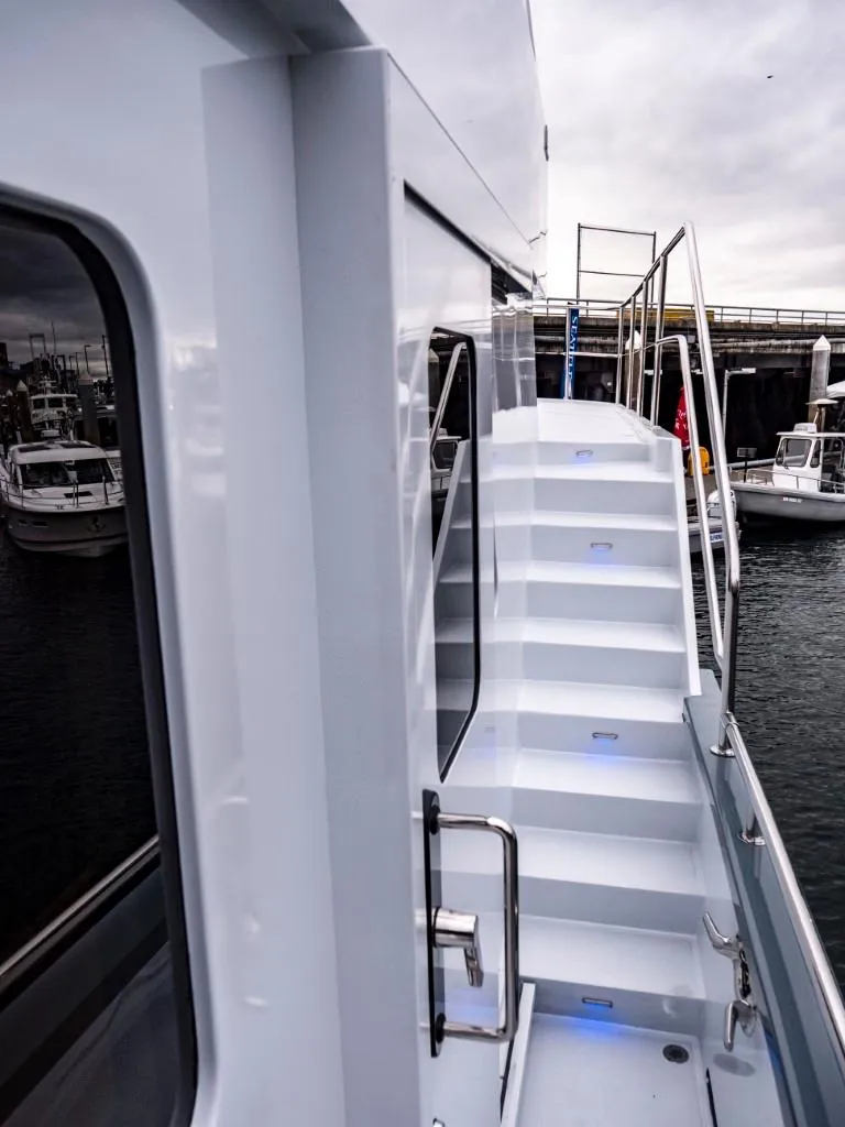 Slide: The Image of 2025 Northern Marine 57 Expedition yacht with exterior stairs and docked boats in the background. - 39