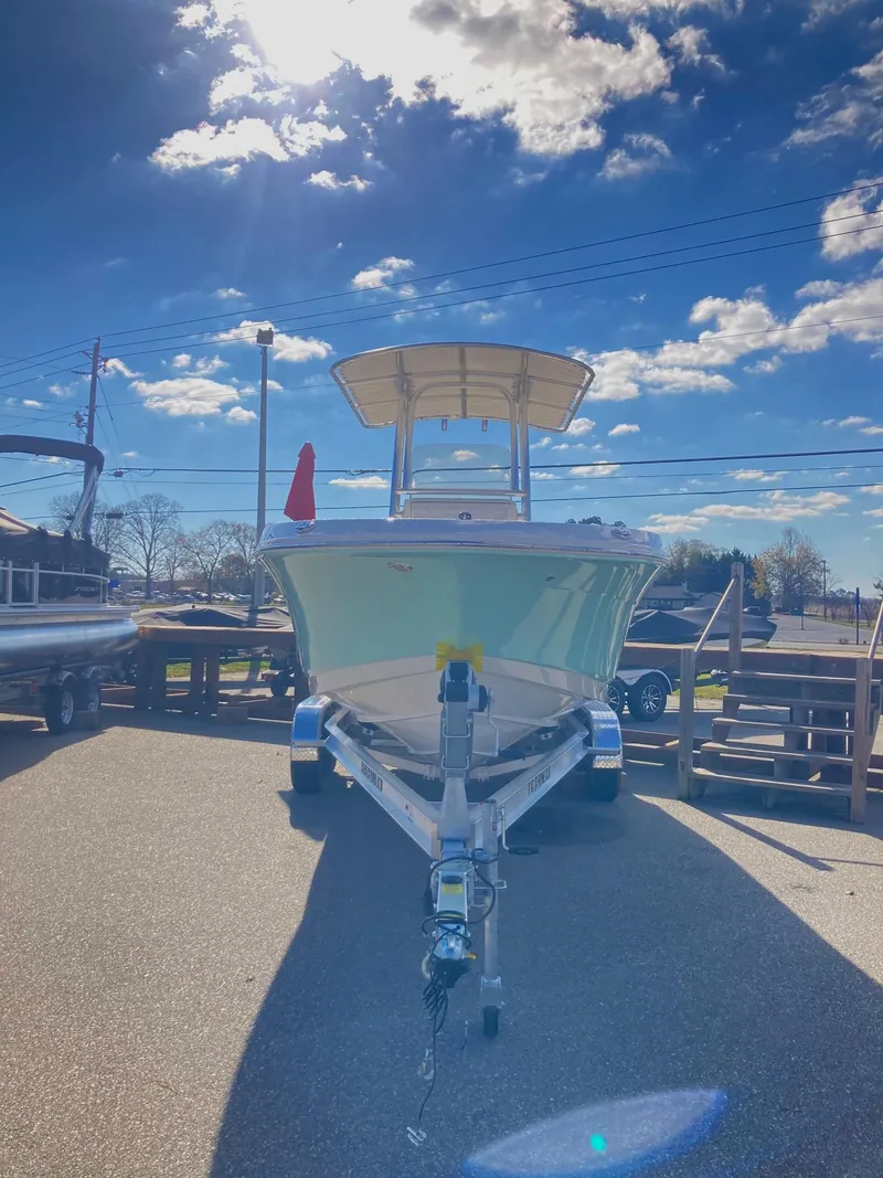 Slide: The Image of 2024 Robalo R200 Center Console boat on a trailer under a bright blue sky. - 2