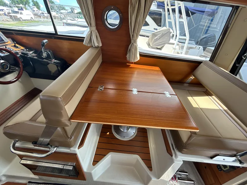 Slide: The Image of Interior of 2020 Ranger Tugs R-27 with wooden table and cushioned seating. - 12