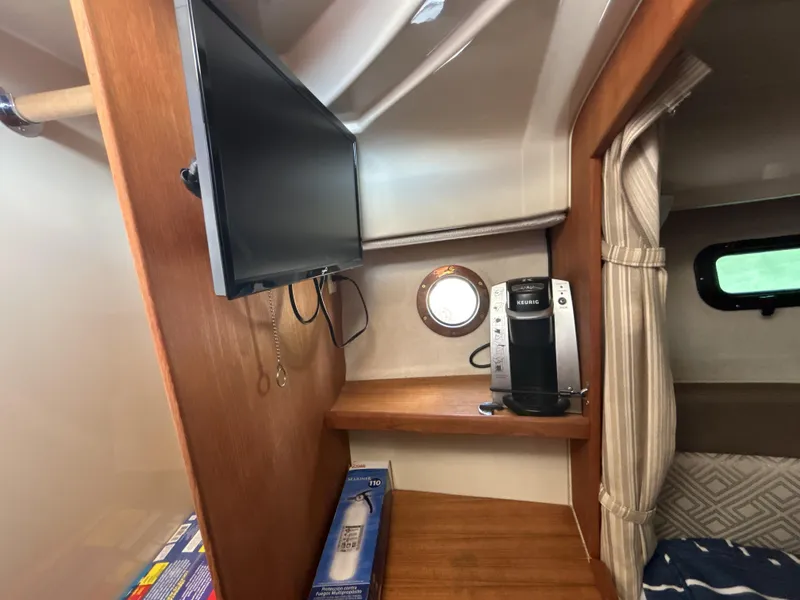 Slide: The Image of 2020 Ranger Tugs R-27 interior with TV, coffee maker, and cozy cabin space. - 14