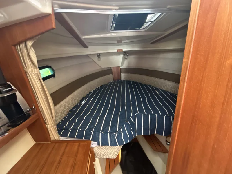 Slide: The Image of 2020 Ranger Tugs R-27 cabin interior with striped bedding and wooden accents. - 6