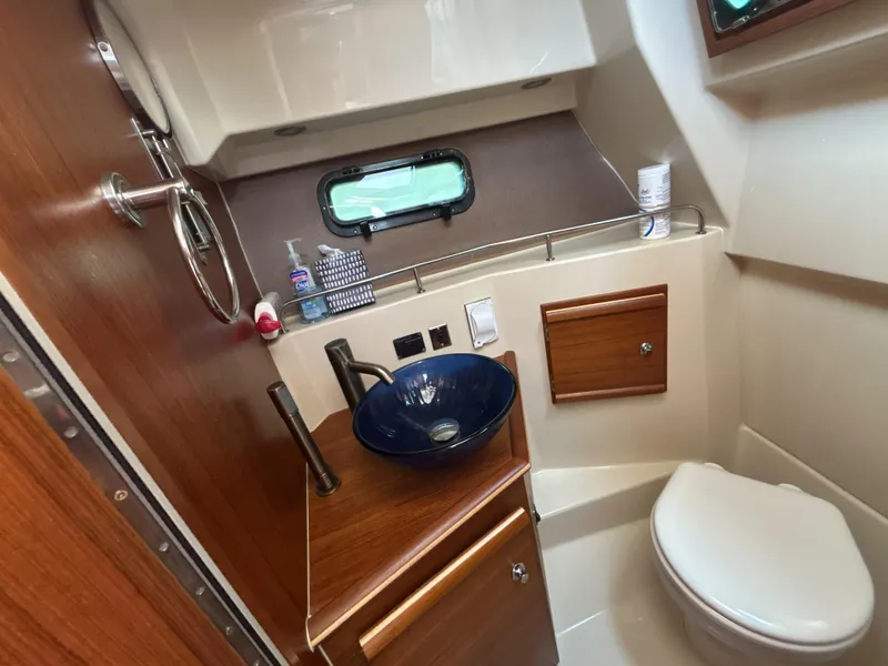 Slide: The Image of 2020 Ranger Tugs R-27 boat bathroom with modern sink, toilet, and wooden cabinetry. - 7