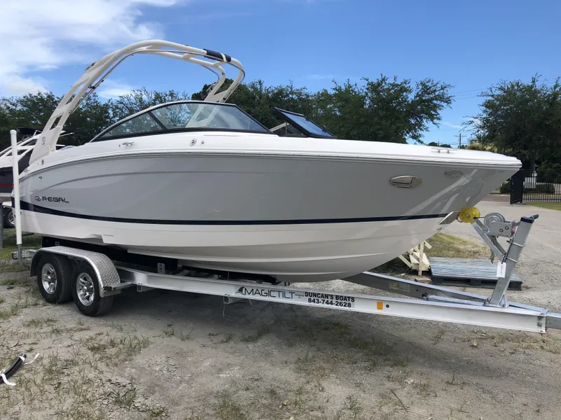 Slide: The Image of 2022 Regal LX4 boat on trailer, parked outdoors under a clear sky. - 0