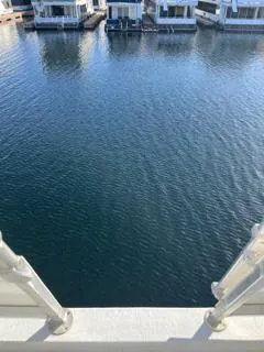 Slide: The Image of Houseboats on a serene lake with rocky hills in the background under a clear blue sky. - 24
