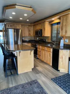 Slide: The Image of Modern kitchen in a 2005 Custom Entourage Shares RV with wooden cabinets and stainless steel appliances. - 6