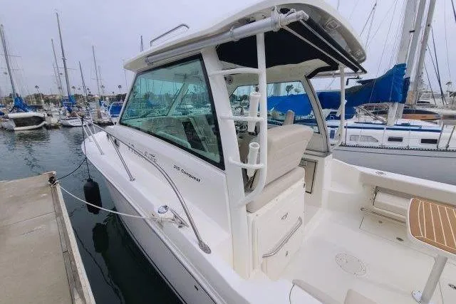 Slide: The Image of 2019 Boston Whaler 315 Conquest docked at marina, showcasing sleek design and spacious cockpit. - 10