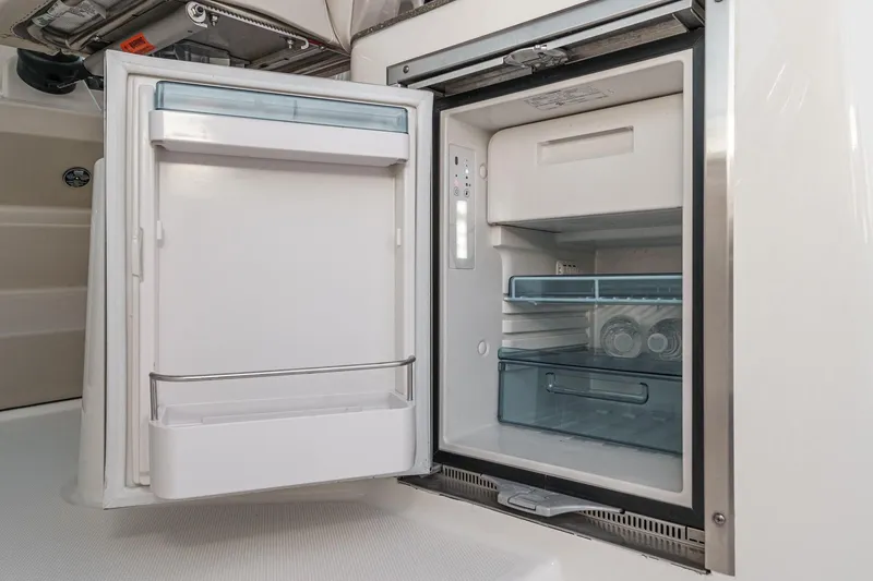 Slide: The Image of 2019 Boston Whaler 315 Conquest boat refrigerator, open with shelves and storage compartments. - 103