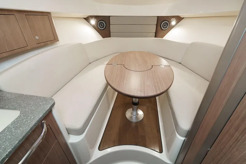 Slide: The Image of 2019 Boston Whaler 315 Conquest cabin interior with cozy seating and wooden table. - 107