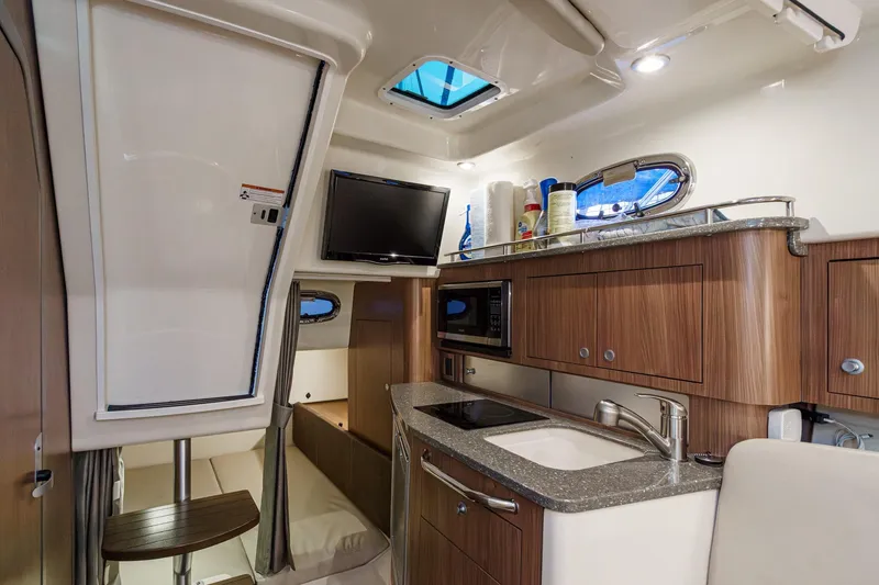 Slide: The Image of 2019 Boston Whaler 315 Conquest cabin interior with kitchenette and seating area. - 110