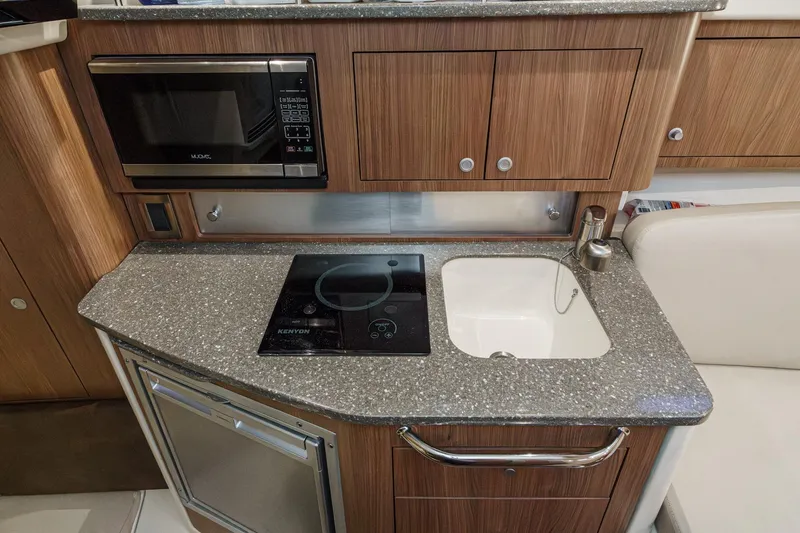 Slide: The Image of 2019 Boston Whaler 315 Conquest galley with microwave, cooktop, and sink. - 112