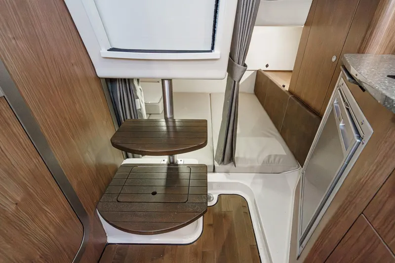 Slide: The Image of 2019 Boston Whaler 315 Conquest cabin interior with wooden steps and compact seating area. - 113