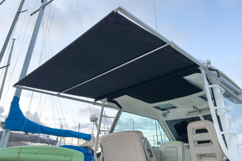 Slide: The Image of 2019 Boston Whaler 315 Conquest boat with extended black canopy, docked at marina. - 120