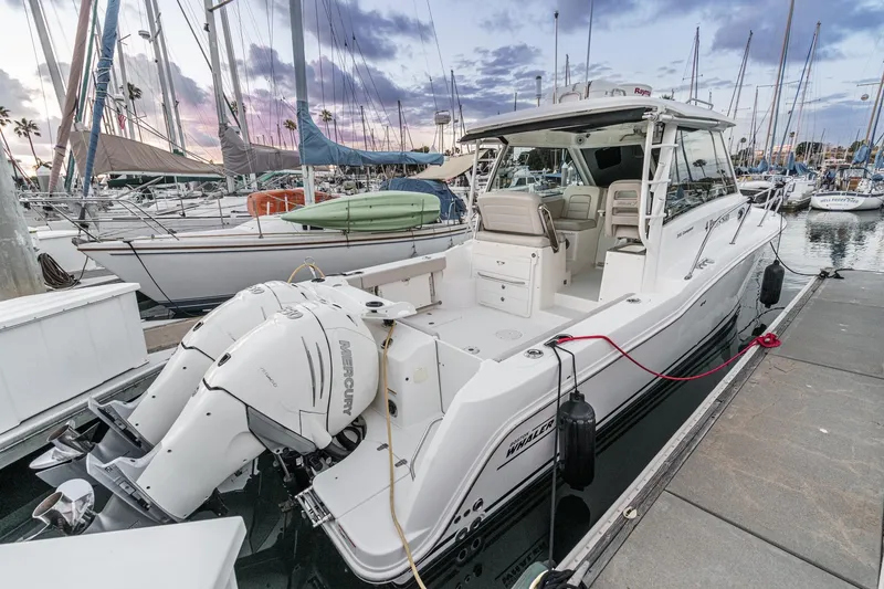 Slide: The Image of 2019 Boston Whaler 315 Conquest docked, featuring twin Mercury outboard engines. - 129