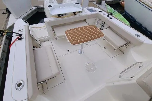 Slide: The Image of 2019 Boston Whaler 315 Conquest boat interior with seating and wooden table. - 17