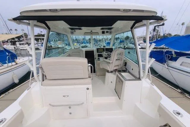 Slide: The Image of 2019 Boston Whaler 315 Conquest boat interior at marina, showcasing helm and seating area. - 18