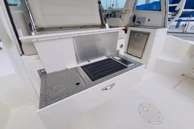 Slide: The Image of 2019 Boston Whaler 315 Conquest boat interior with kitchenette and seating area. - 20