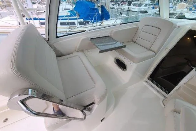 Slide: The Image of 2019 Boston Whaler 315 Conquest interior with seating and table, docked at marina. - 23
