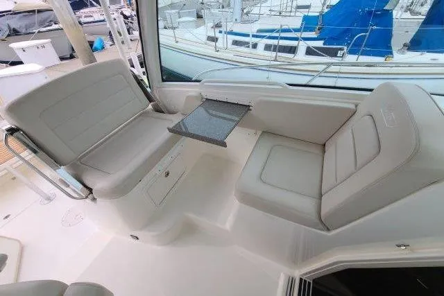 Slide: The Image of 2019 Boston Whaler 315 Conquest interior seating area with foldable table, docked at marina. - 24