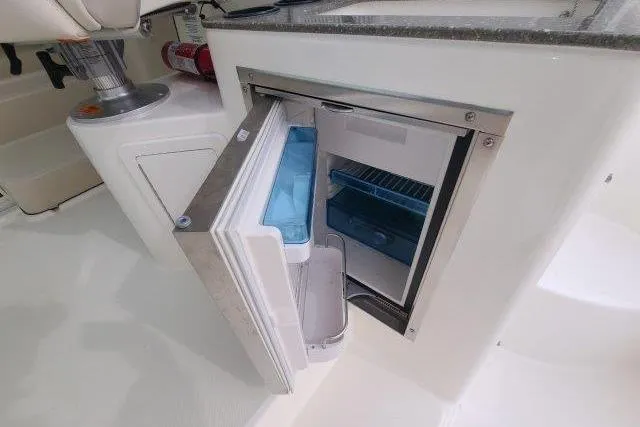 Slide: The Image of 2019 Boston Whaler 315 Conquest boat interior with open mini fridge. - 26