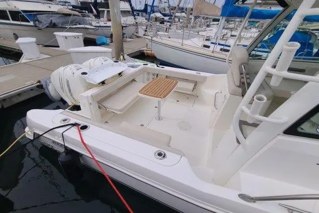 Slide: The Image of 2019 Boston Whaler 315 Conquest docked, showcasing spacious deck and seating area. - 5