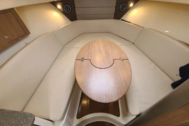 Slide: The Image of 2019 Boston Whaler 315 Conquest cabin interior with beige seating and wooden table. - 55
