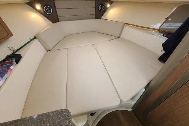 Slide: The Image of 2019 Boston Whaler 315 Conquest cabin interior with cushioned seating and ambient lighting. - 56