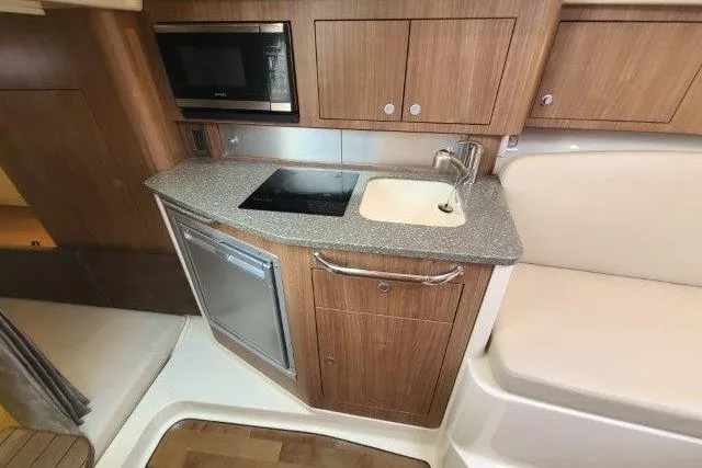 Slide: The Image of 2019 Boston Whaler 315 Conquest interior kitchen with sink, stove, and microwave. - 58