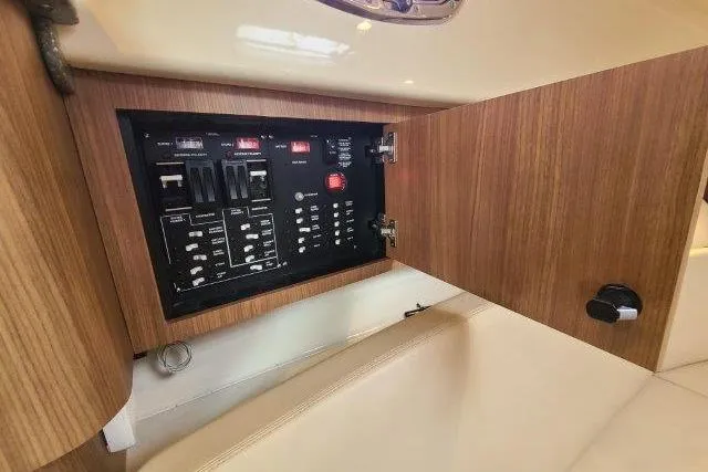 Slide: The Image of Electrical panel inside a 2019 Boston Whaler 315 Conquest boat, featuring wooden cabinetry. - 59